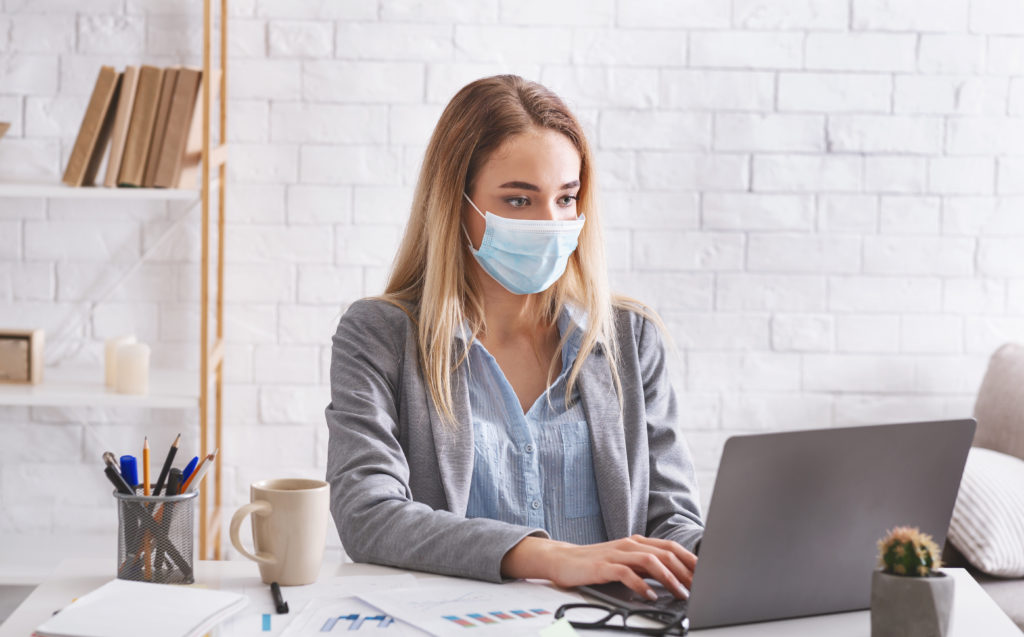 Remote work during epidemic of COVID-19 virus. Woman works in protective mask